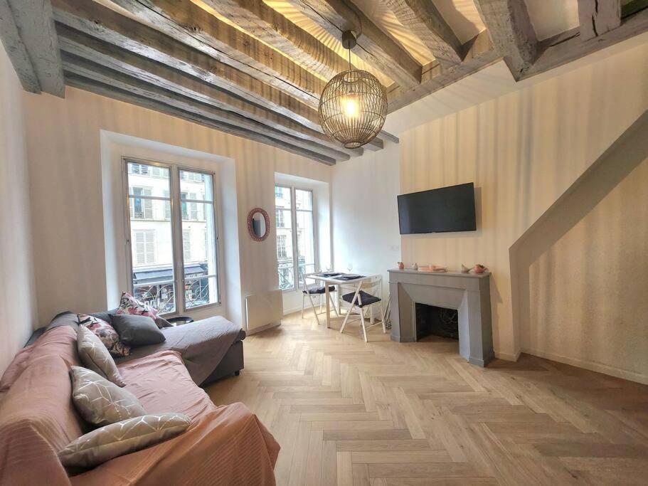 un salon avec un canapé, une table et une télévision dans l'établissement Appartement - Versailles centre, à Versailles