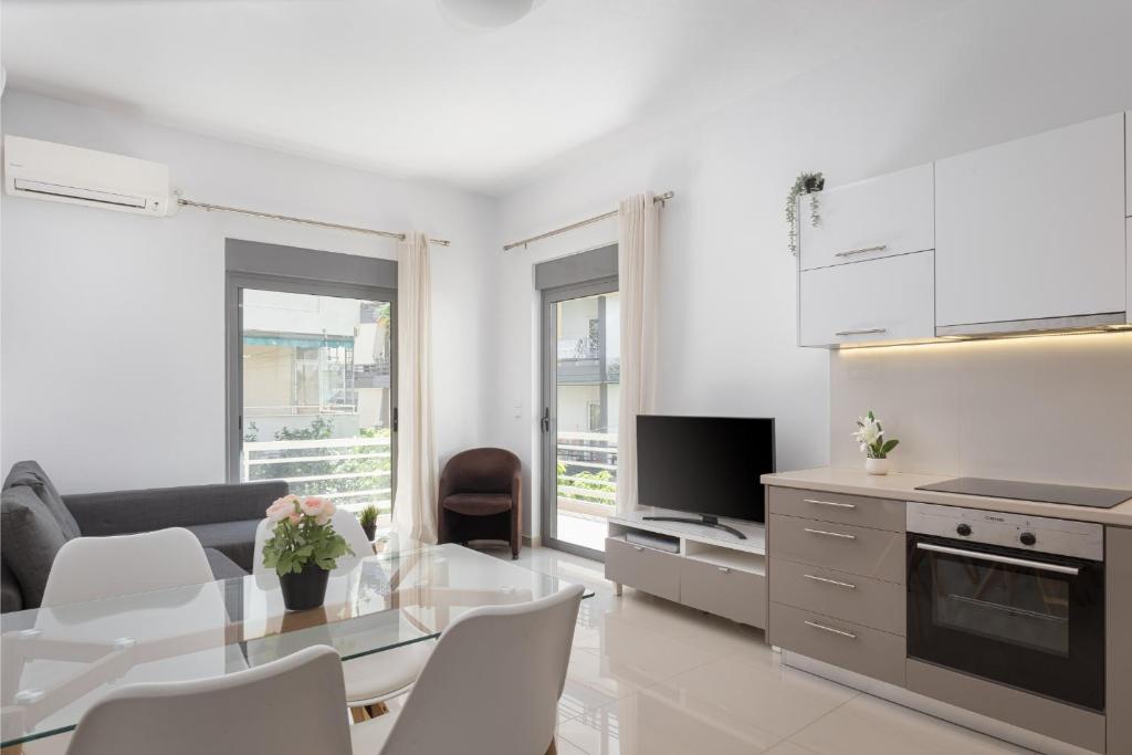 sala de estar blanca con mesa y cocina en Varkiza Seaside Apartment, en Vari