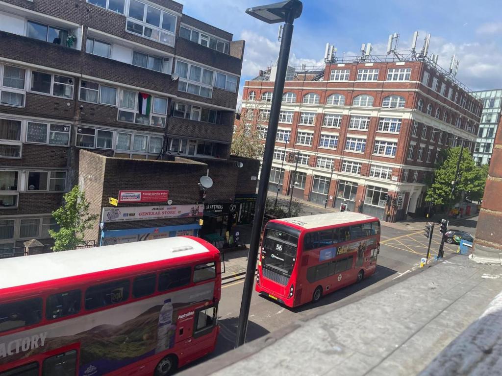 un autobús rojo de dos pisos conduciendo por una calle de la ciudad en Charming 1-Bed Apartment in London, en Londres