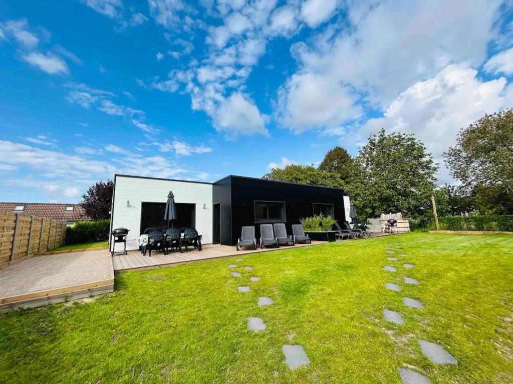 une maison noire et blanche avec une cour dans l'établissement Gîte neuf en ossature bois à 5 minutes de Berck., à Verton