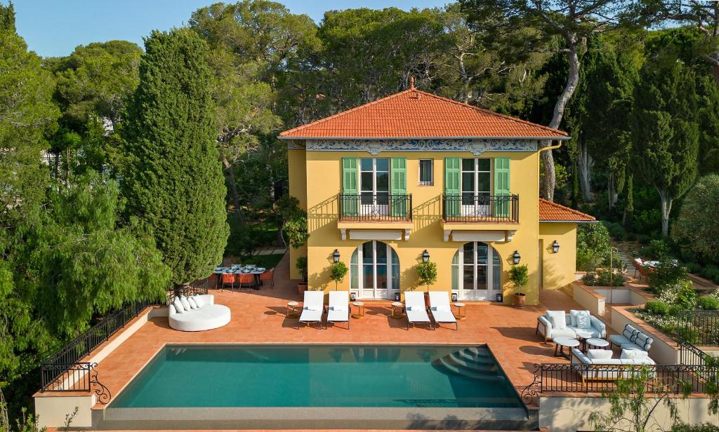 a yellow house with a swimming pool in front of it at Grand-Hôtel du Cap-Ferrat, A Four Seasons Hotel in Saint-Jean-Cap-Ferrat