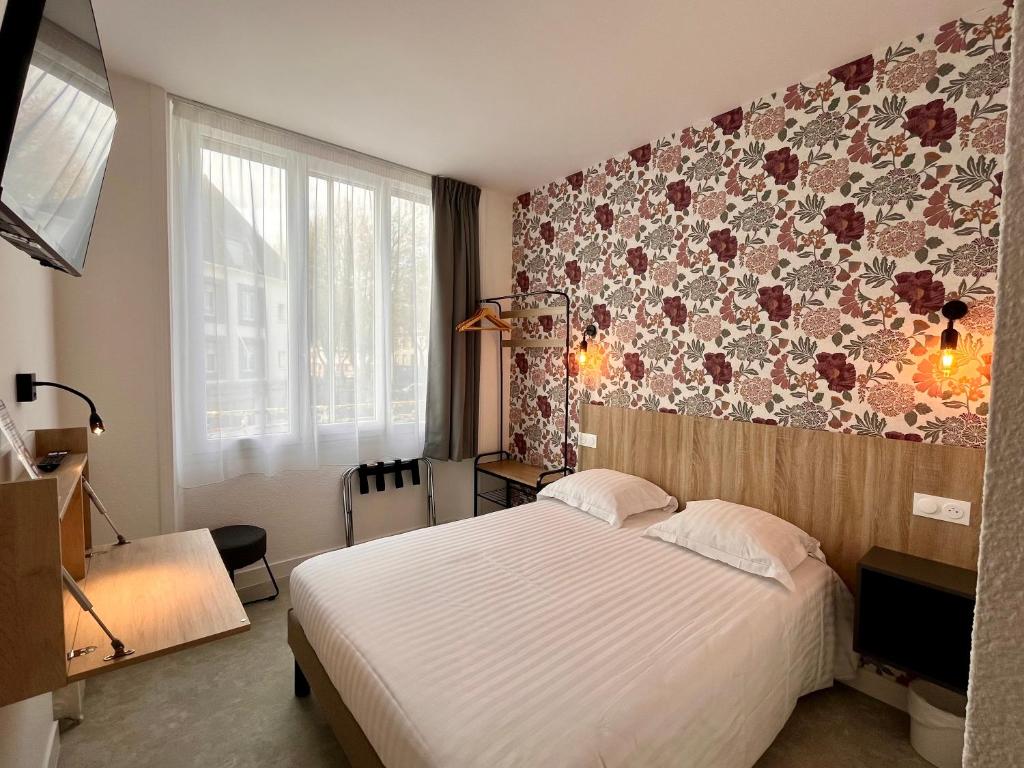 a bedroom with a bed and a floral wall at Hôtel Le Keroman in Lorient