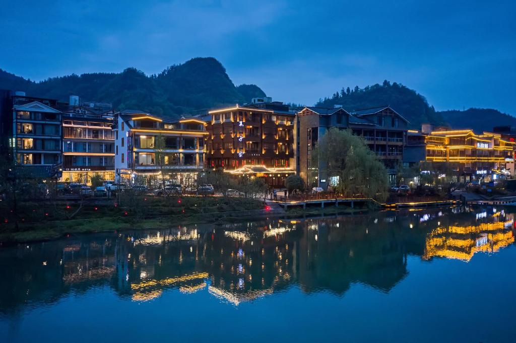 un grupo de edificios junto a un río por la noche en Lee's Boutique Resort en Zhangjiajie
