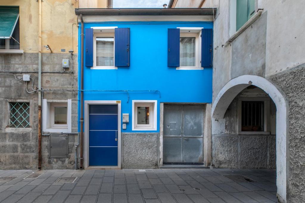 un bâtiment bleu avec une porte et une arche dans l'établissement Ca' Balin - Chioggia, à Chioggia