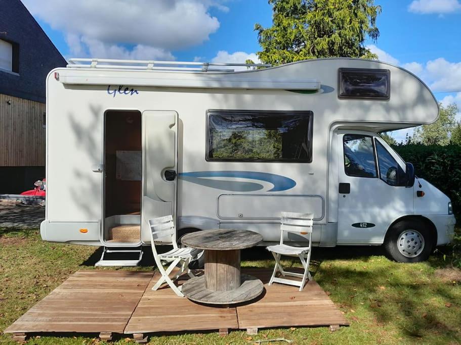 una roulotte bianca con tavolo e sedie accanto di Camping-car calme et confortable a Carentoir
