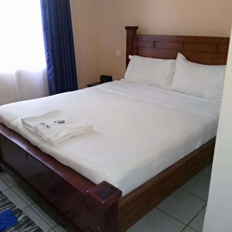 a bed with a white shirt sitting on top of it at New Carnation Pangani Hotel in Nairobi