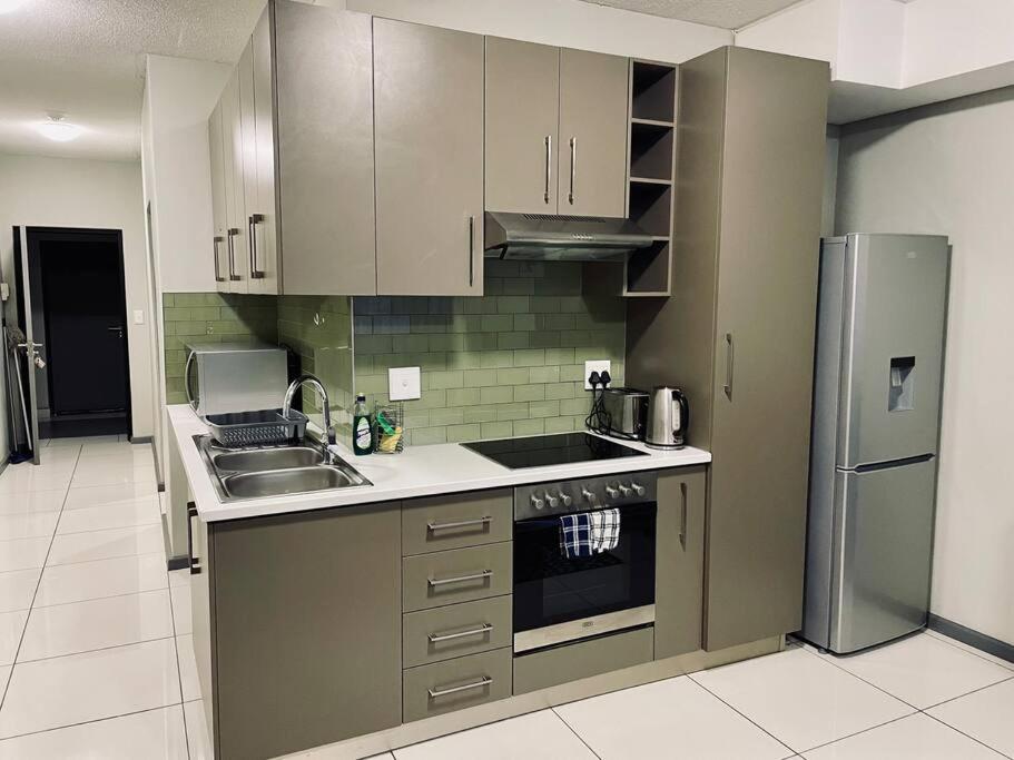 eine Küche mit einer Spüle und einem Kühlschrank in der Unterkunft Cozy Escape in Windhoek