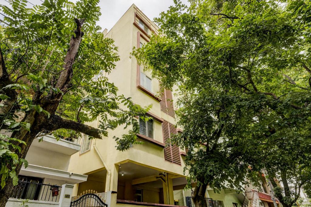 un bâtiment jaune avec des arbres devant lui dans l'établissement Wandr.Altair - Indiranagar, Near Rameshwaram Cafe, à Bangalore