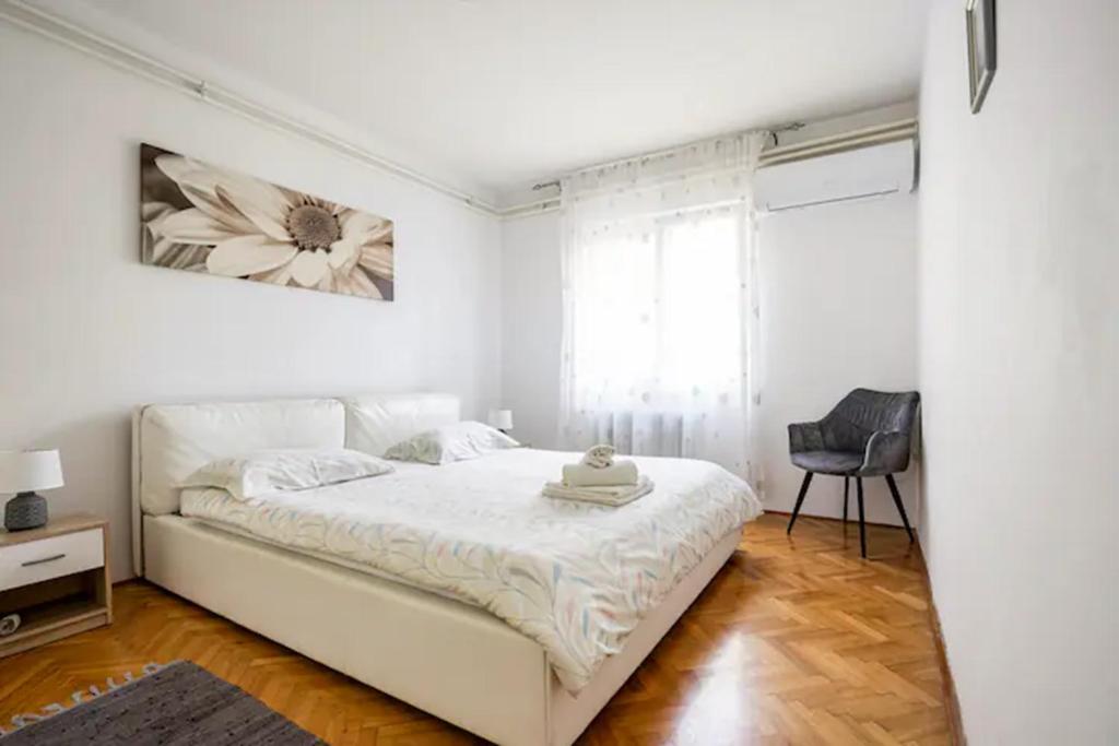 een witte slaapkamer met een wit bed en een stoel bij Apartment Tomas,,,Spacious house with private parking,terrace,5G Internet,,,,, in Zadar