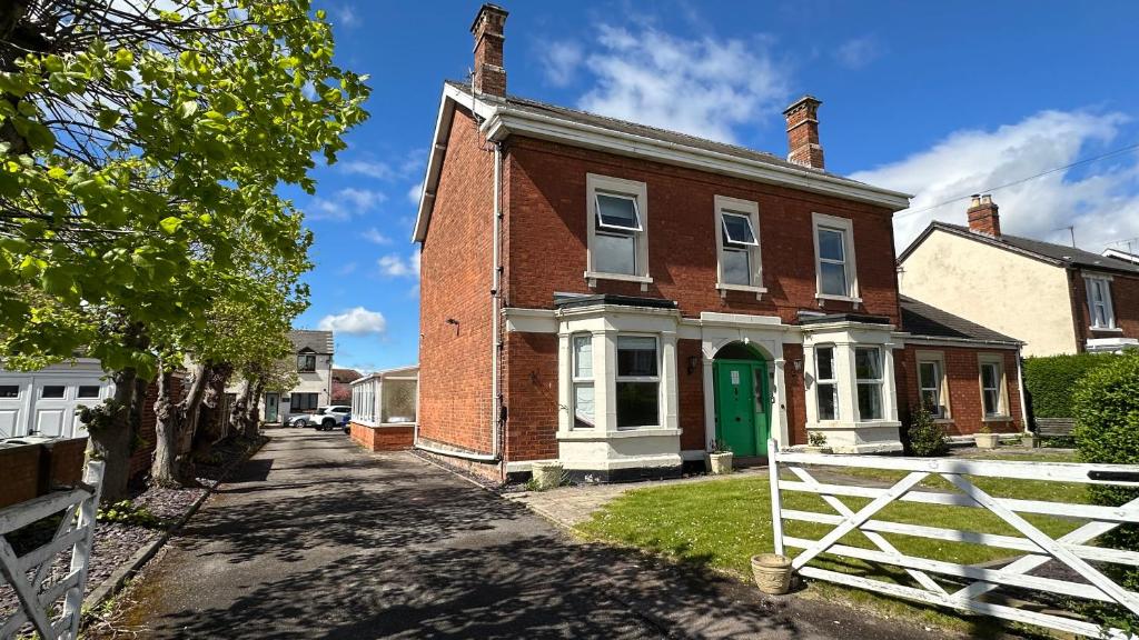 a brick house with a green door on a street at Very Spacious 9 Bedroom House-Garden-Parking for 6 in Gloucester