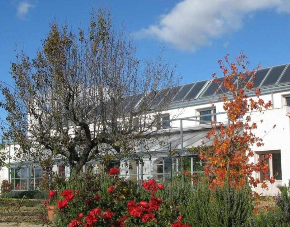 un edificio bianco con un albero e dei fiori di fronte di Casa Rural Marialba a Monte la Reina