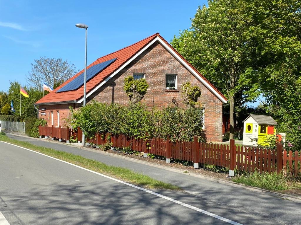 una casa de ladrillo rojo con una valla al lado de una carretera en Ferienhaus am Bunderhammrich 25184 en Bunde