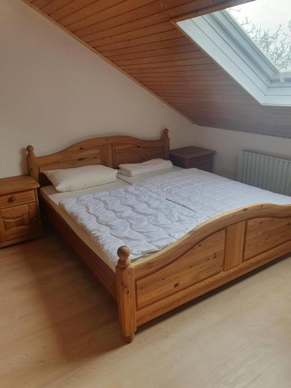 1 dormitorio con cama grande de madera y tragaluz en Pension zum Hollerbusch, en Heilbach