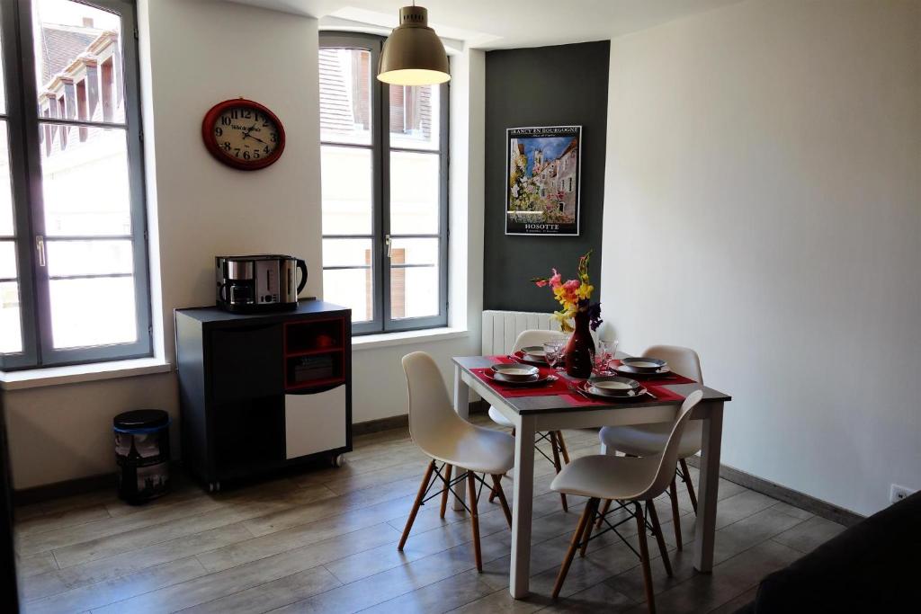a dining room with a table and chairs and a clock at Sur les Pas de Cadet Roussel in Auxerre