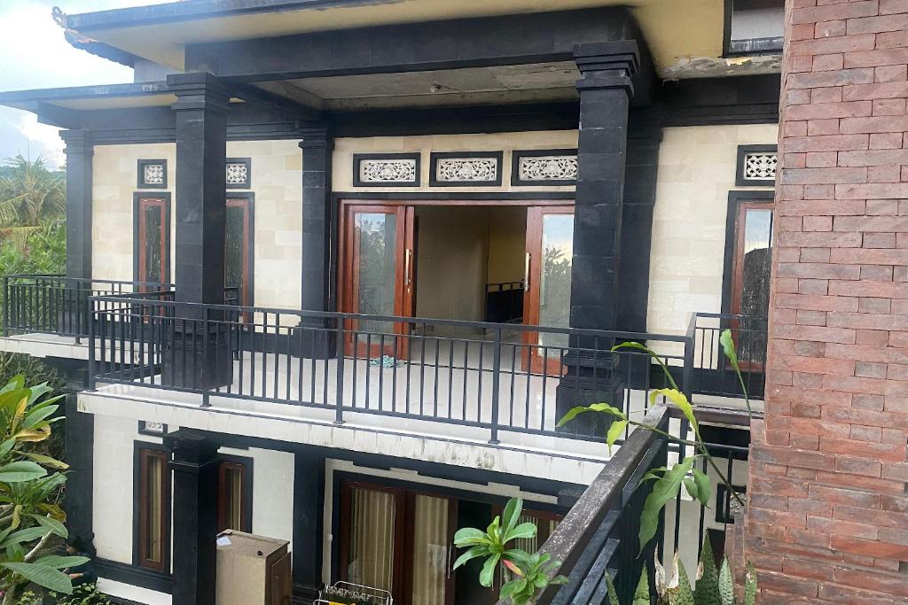 a house with a balcony and a brick building at Capital O 93844 Arta Adi Homestay in Bangli