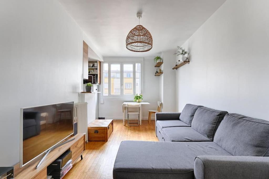 een woonkamer met een bank en een flatscreen-tv bij Résidor - Warm and bright 4P apartment! in Boulogne-Billancourt