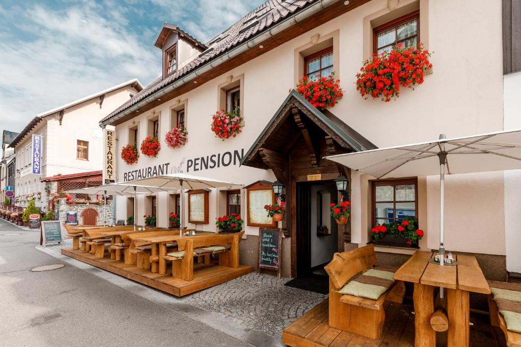 un ristorante con tavoli e ombrelloni in legno su una strada di Penzion a Apartmány Daro a Boží Dar