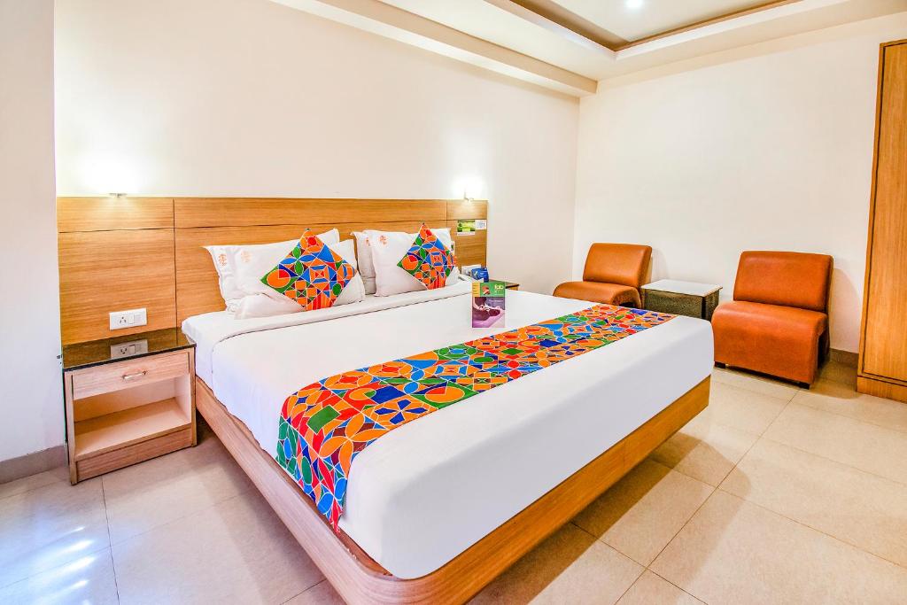 a bedroom with a large bed and a chair at FabHotel Prime Royal Castle Gandhipuram in Coimbatore