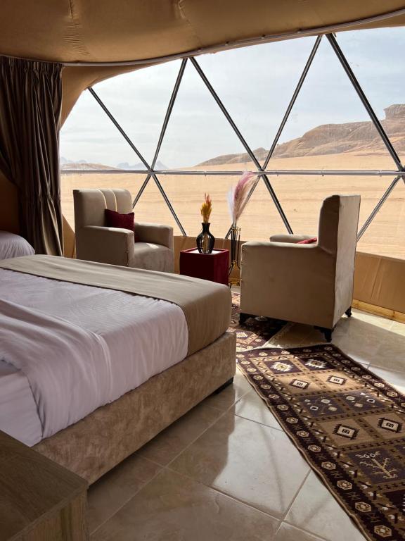 1 dormitorio en una tienda de campaña con 1 cama y sillas en Wadi Rum Rose camp, en Wadi Rum