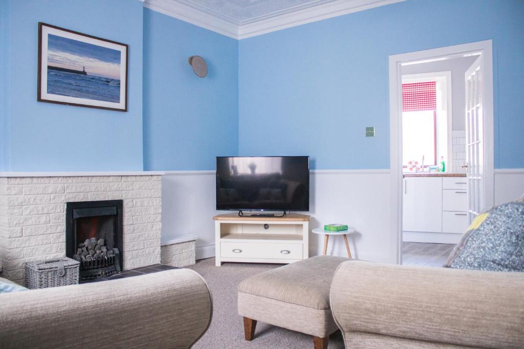 a blue living room with a tv and a fireplace at Beach House in Berwick Upon Tweed - 2 Double Bedrooms in Spittal
