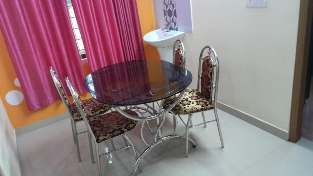 a glass table and two chairs in a room at SNOWVALLEY RESIDENCY Vagamon in Vagamon