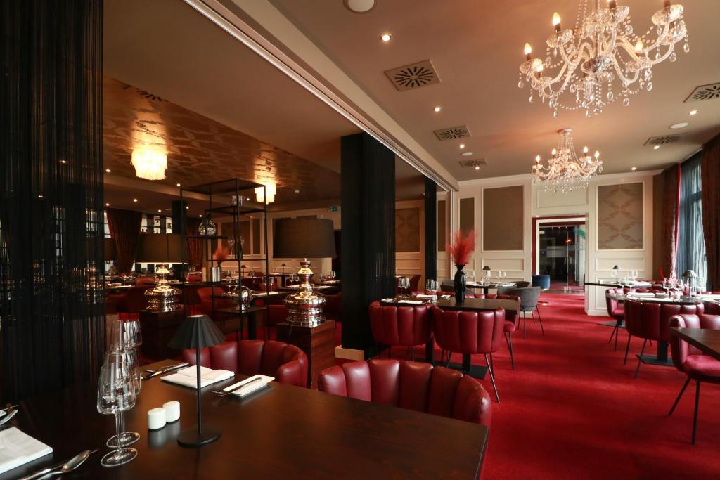 a restaurant with red chairs and tables and a chandelier at Hotel Haverkamp in Bremerhaven