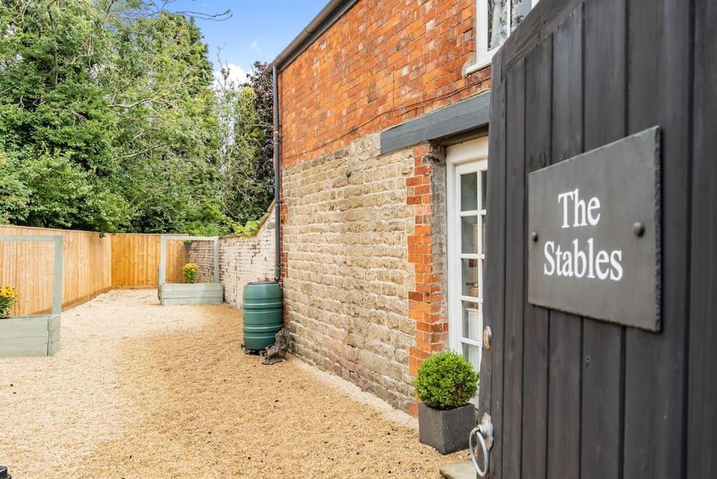 a brick building with a sign that reads the stables at 2 bedroom cottage in Old Town in Swindon