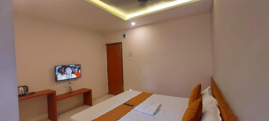 een slaapkamer met een bed en een tv aan de muur bij Hotel Kapish International Solapur 400 mts from Bus Stand and 500 mtr from railway station in Solapur