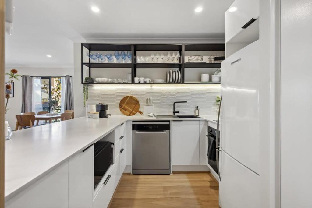 cocina con armarios blancos y encimera blanca en Jolly on James- 2BDR, en Perth