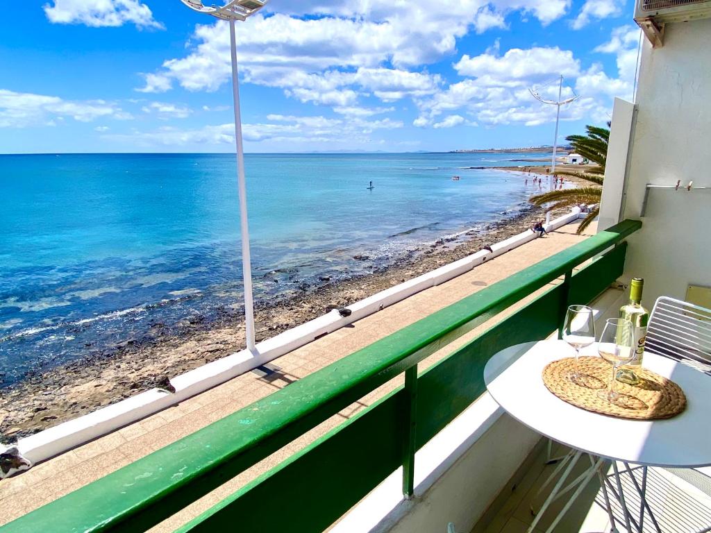een balkon met een tafel en uitzicht op het strand bij Lanzarote Frente al Mar in San Bartolomé