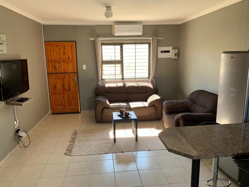 a living room with a couch and a tv at Proventures Self-catering House in Ondangwa