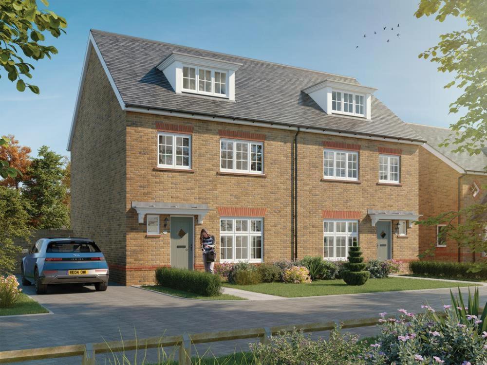 a woman standing in front of a brick house at 3 Bedroom, 3.5 Bathroom House, Goodwood Racecourse in Lavant