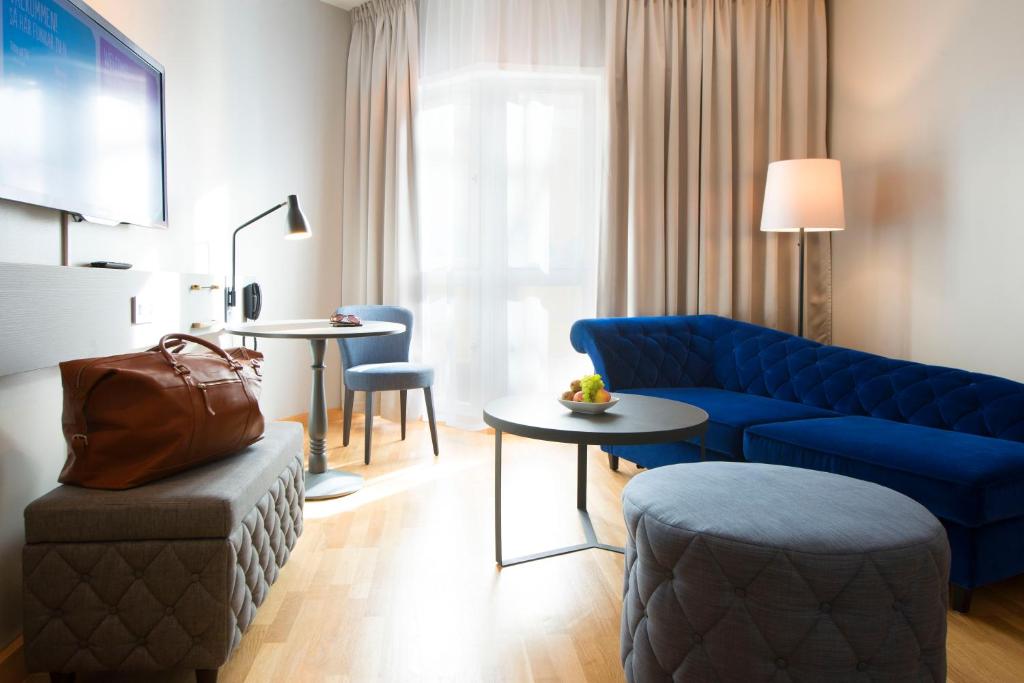 a living room with a blue couch and a table at Scandic Skellefteå in Skellefteå