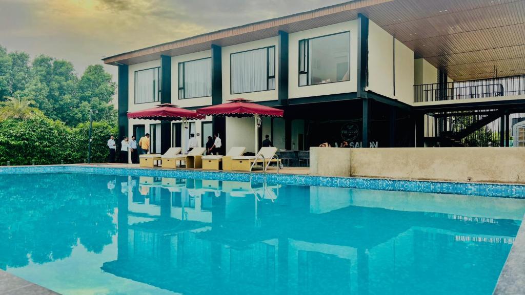 a house with a swimming pool with chairs and umbrellas at Vintclub Resort in Lucknow