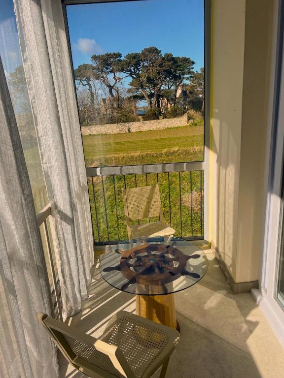 a table and chairs on a balcony with a large window at Studio vue sur mer avec véranda - Roscoff in Roscoff