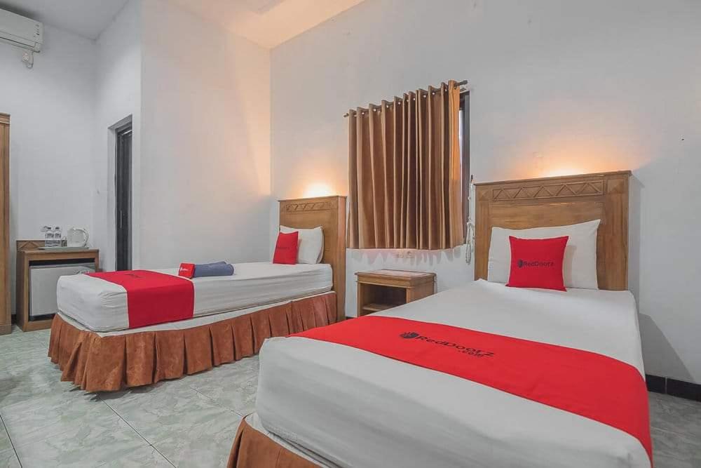 a bedroom with two beds with red and white sheets at Ilfa Guest House syari'ah in Jatiwangi