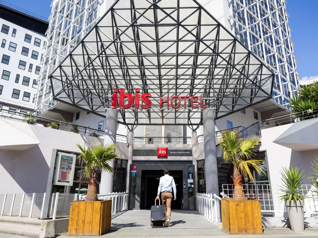 a man with a suitcase walking into a bus station at ibis Bordeaux Centre Meriadeck in Bordeaux