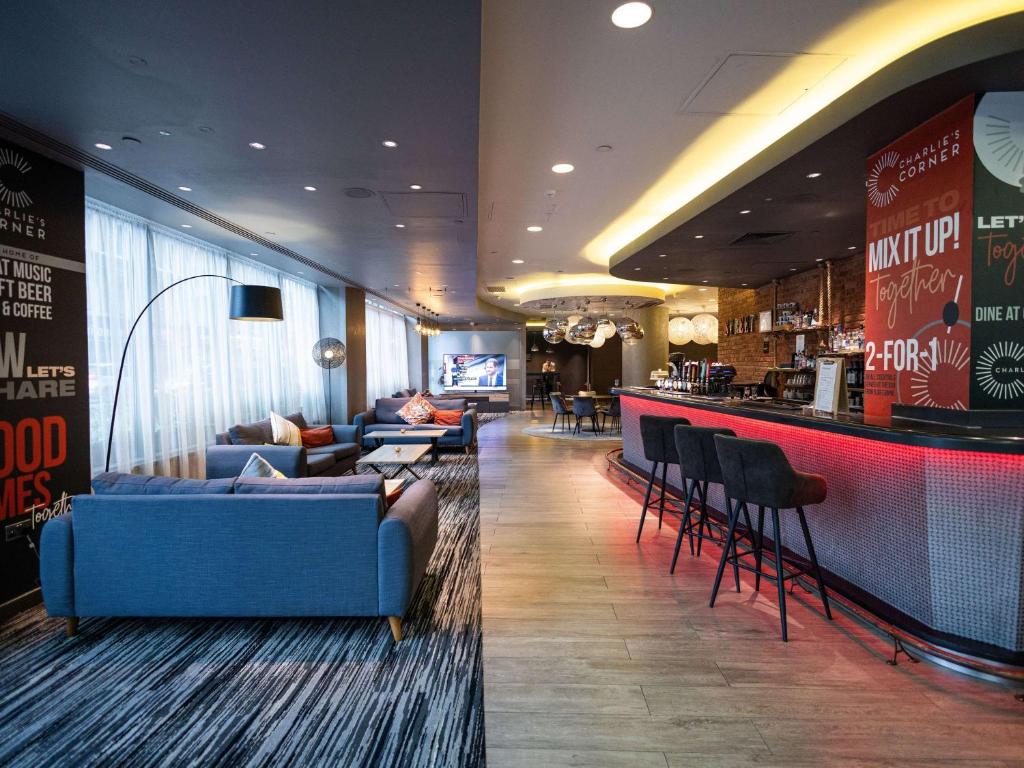 a hotel lobby with a bar with couches and a counter at ibis London City - Shoreditch in London