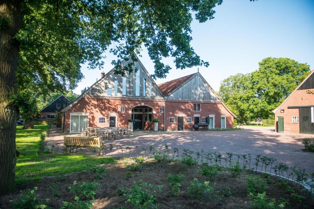 een oude bakstenen schuur met een gambrel dak bij Erfgoed Bossem in Lattrop