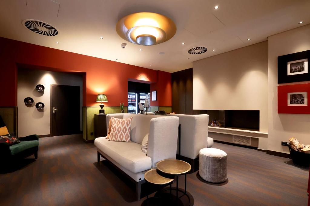 a living room with a white couch and a television at Best Western Plus Hotel St. Raphael in Hamburg