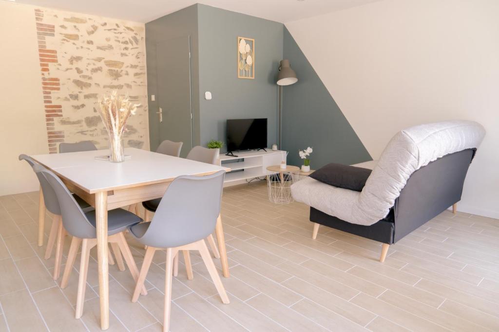sala de estar con mesa, sillas y sofá en La Vie En Gîte (Le Scandinave), en Sainte-Florence