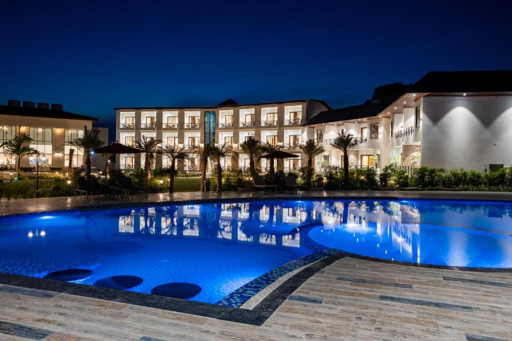 兰纳加Shervani Pebbles & Pines Resort & Spa, Corbett的夜晚建筑物前的游泳池