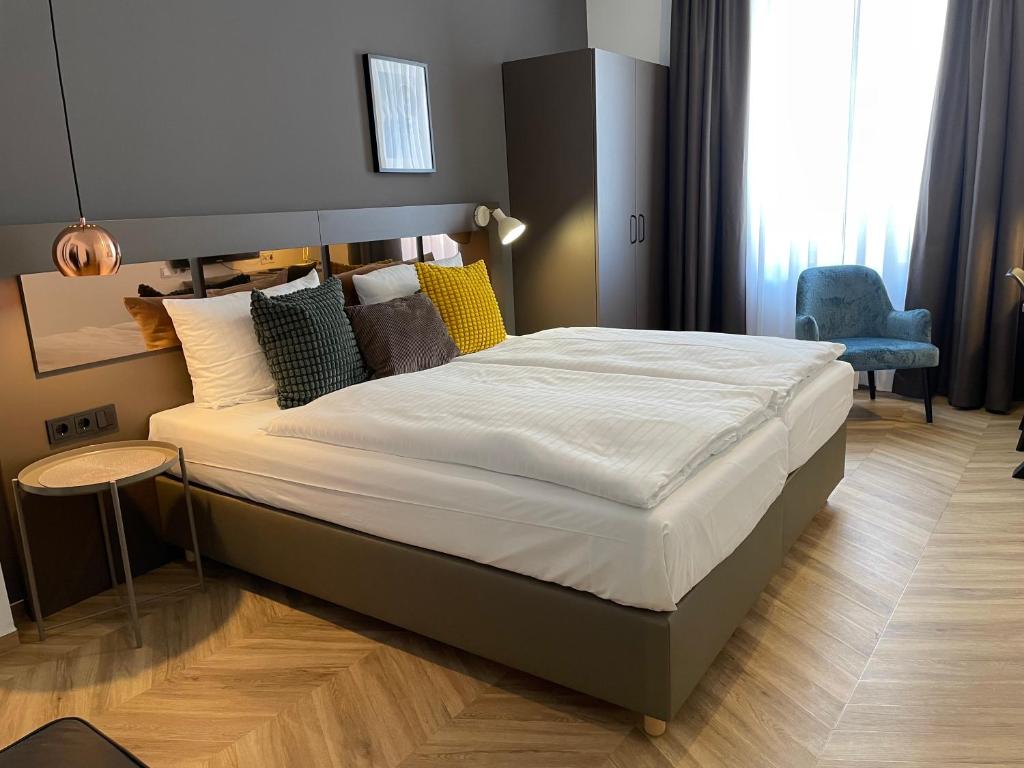 ein großes Bett in einem Schlafzimmer mit einem blauen Stuhl in der Unterkunft Dom Hotel in Osnabrück