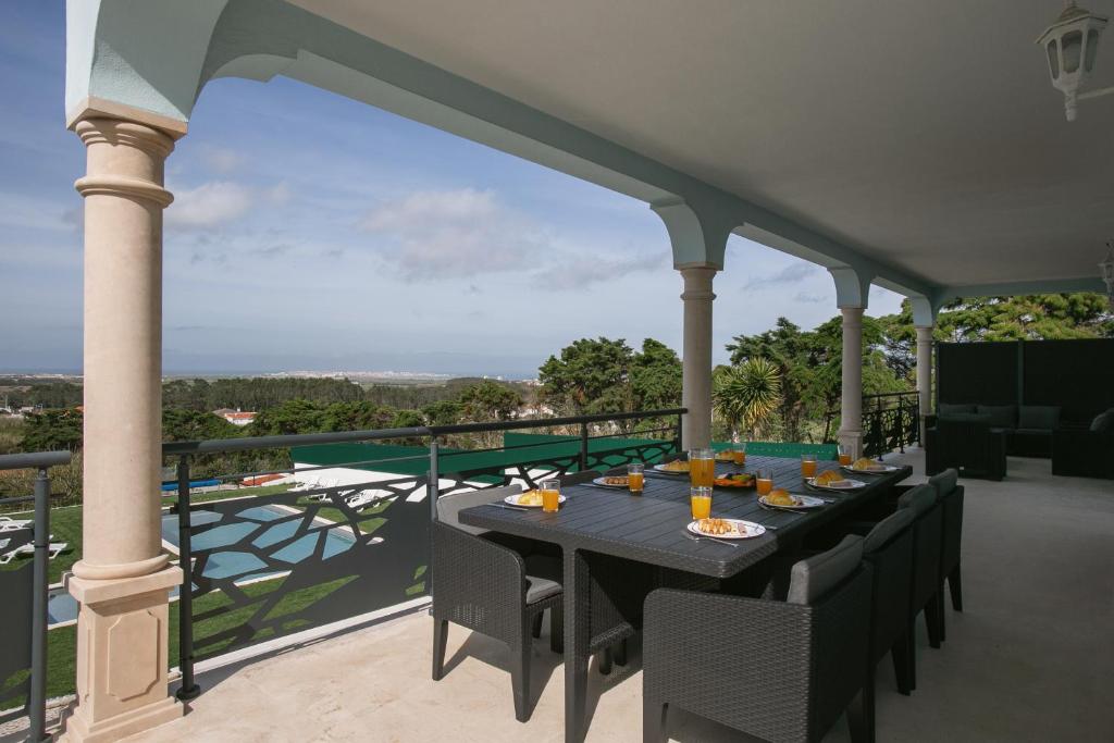 a table on a balcony with a view of the ocean at Bela Vista in Atouguia da Baleia