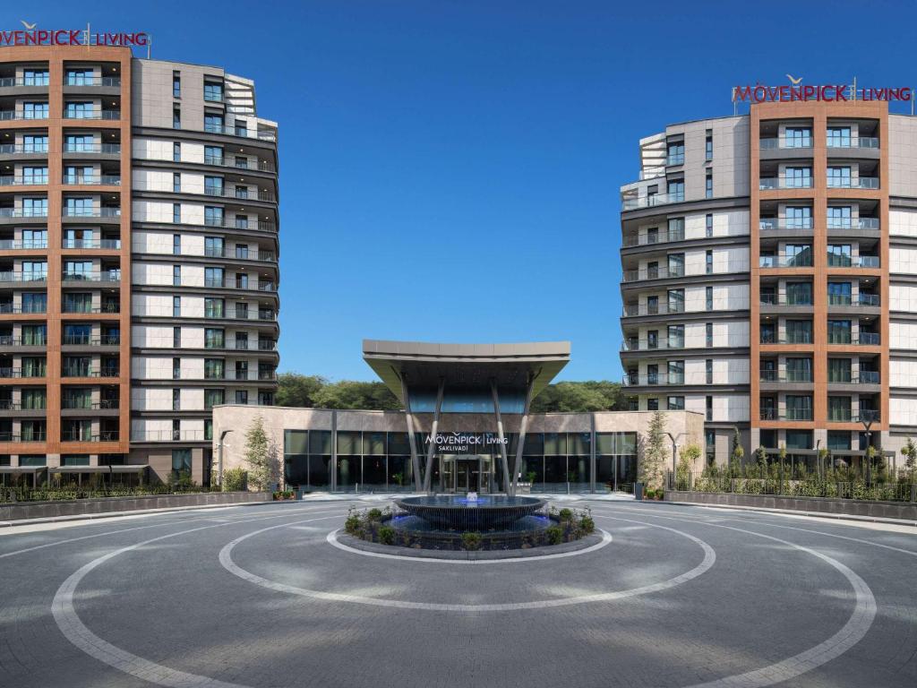 a building with a fountain in front of two tall buildings at Mövenpick Living Istanbul Saklivadi in Istanbul