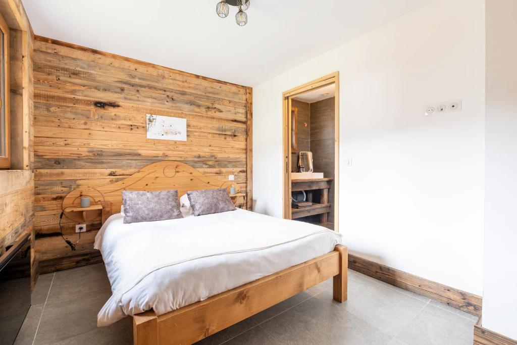 a bedroom with a wooden wall and a bed at La cabane du cerf in Les Allues