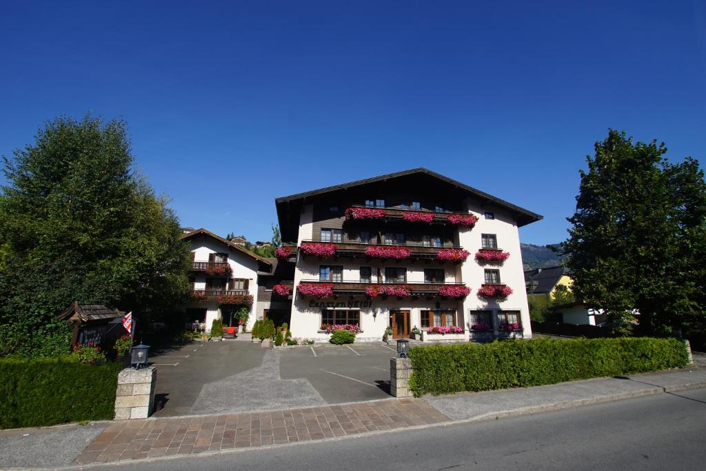 a large white building with red flowers on it at Pension Heidi in Kaprun