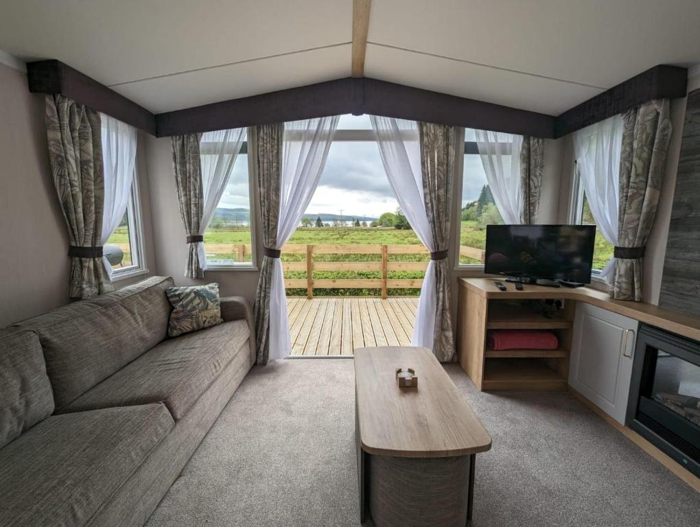 ein Wohnzimmer mit einem Sofa, einem TV und einem Tisch in der Unterkunft Swift Bordeaux Sea View 15 in Dunoon