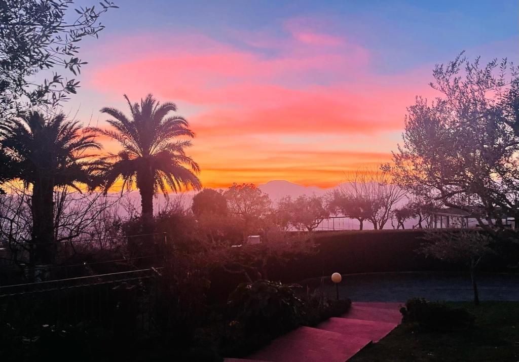 un coucher de soleil avec des palmiers et des montagnes en arrière-plan dans l'établissement Villa Mandetta B&B, à Santo Stefano del Sole