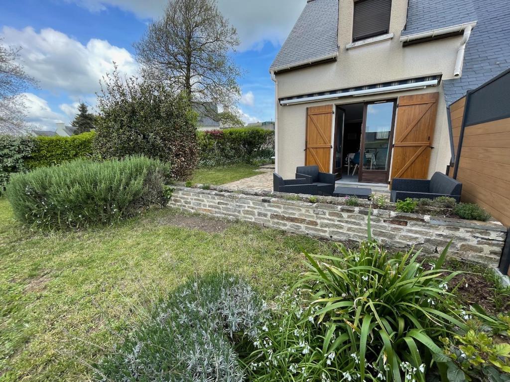 une maison blanche avec une fenêtre et une cour dans l'établissement Maison paisible, piscine, plages à 500m, à Clohars-Carnoët